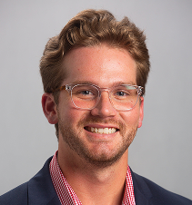 A professional man with glasses smiling in a business setting, representing Intelligent Office franchise opportunities.
