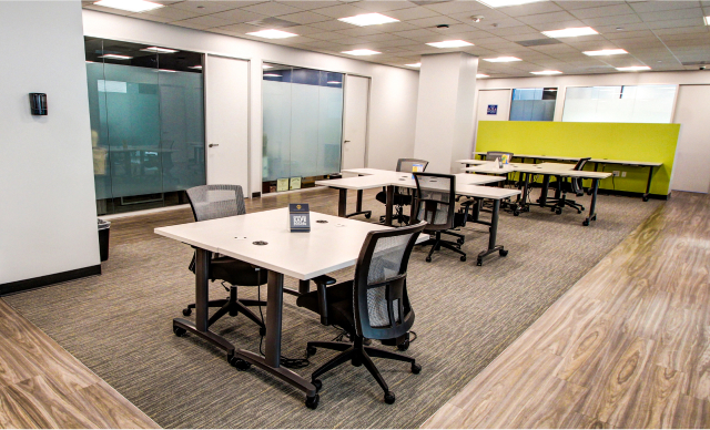 Modern office co-working space with white desks and ergonomic chairs, bright lighting, glass walls, and contemporary interior design for intelligent office franchising opportunities.