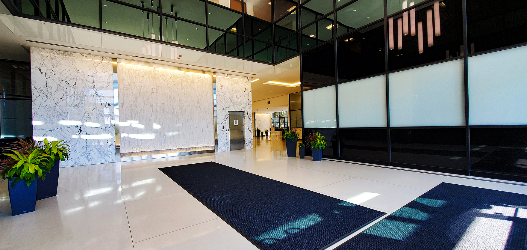 Modern corporate office lobby with marble accents and sleek glass walls, showcasing professional workspace environment and inviting entrance for business clients.