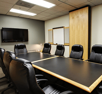 Conference room with black leather chairs and a large table, ideal for meetings and business discussions.