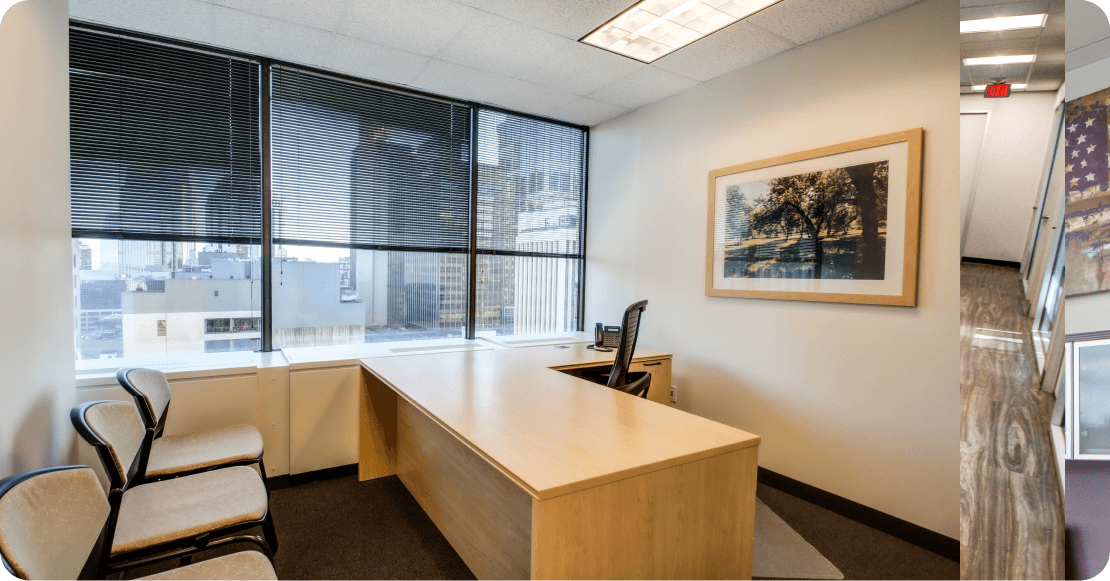 Bright office space with large windows, a wooden desk, chairs, and wall art, ideal for business meetings and franchising discussions.